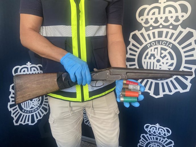 Un agente muestra la escopeta de cañones recortados intervenida al supuesto autor del tiroteo a un varón en la Barqueta