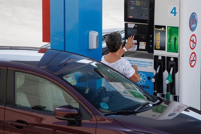 Archivo - Una mujer antes de echar carburante a su vehículo en una estación de servicio