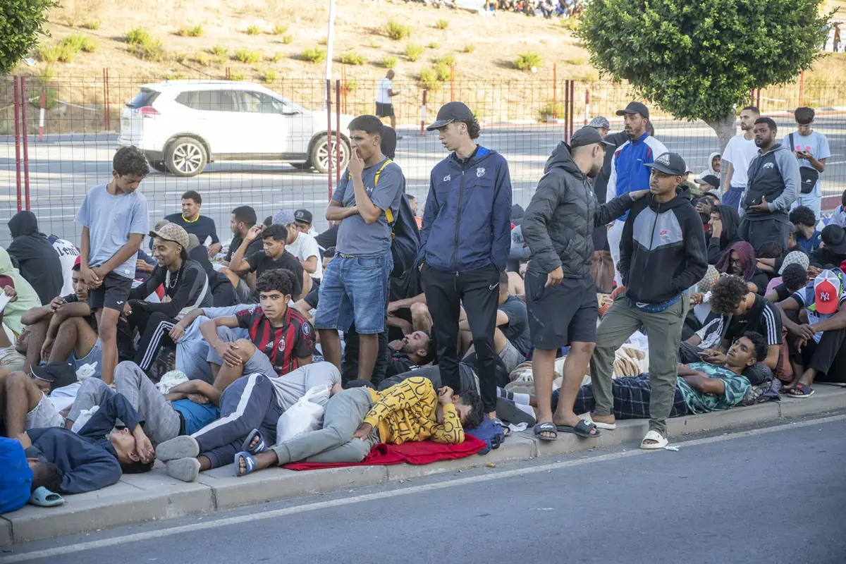 Migrantes esperan haciendo cola para ser atendidos por servicios de acogida en Ceuta
