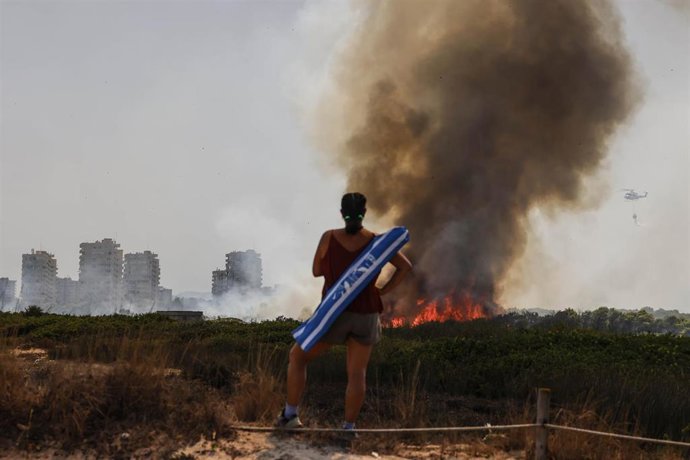 Una mujer observa el incendio de El Saler desde la playa