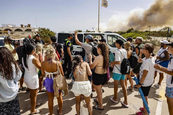 Varias personas desalojan la playa durante un incendio forestal, a 27 de agosto de 2026, en la Gola de Pujol, El Saler, Valencia