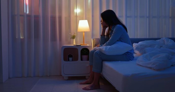 Archivo - Mujer sentada en la cama despierta por la noche.
