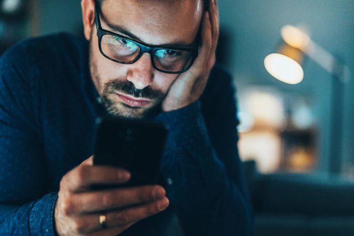 Archivo - Imagen de recurso de un hombre mirando un vídeo a través de su móvil.