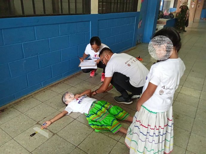 Expertos sobre el crecimiento infantil en barrios vulnerables de Honduras examinan el estado de salud de una menor en presencia de otra joven