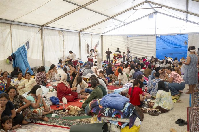 Varios menores migrantes se refugian bajo una carpa.