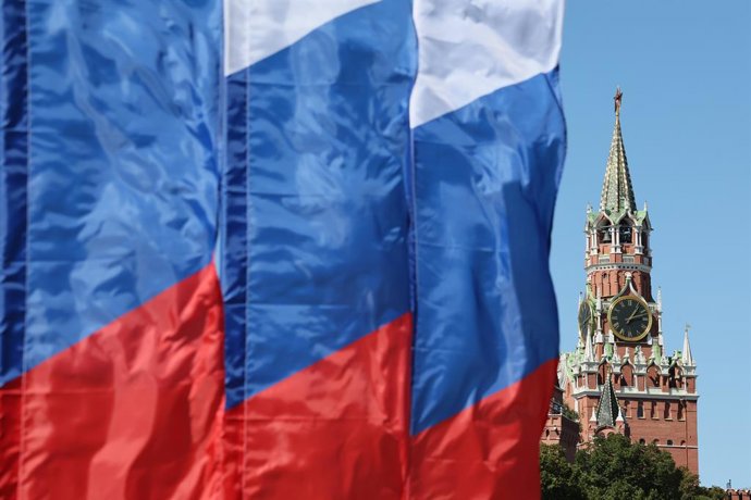 RUSSIA, MOSCOW - AUGUST 23, 2026: Flags of Russia wave, with Spasskaya Tower of the Moscow Kremlin seen in the background