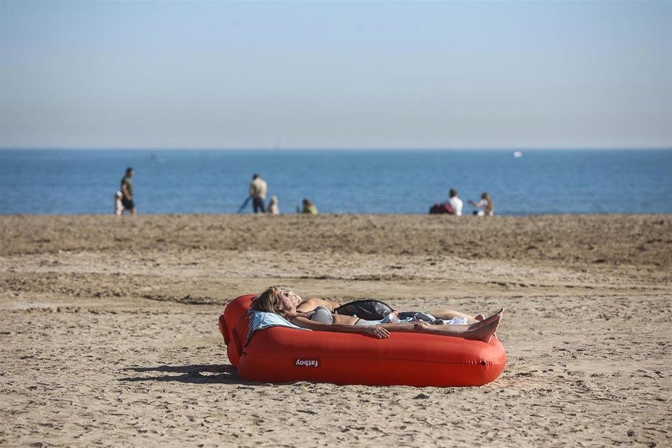 Archivo - Una mujer toma el sol tumbada en un flotador, en la playa de la Malvarrosa, en imagen de archivo.