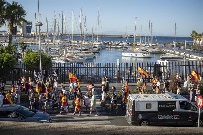 Numerosas personas portan claveles y banderas de España durante una manifestación ante la Delegación del Gobierno, a 28 de agosto de 2026, en Ceuta (España). 