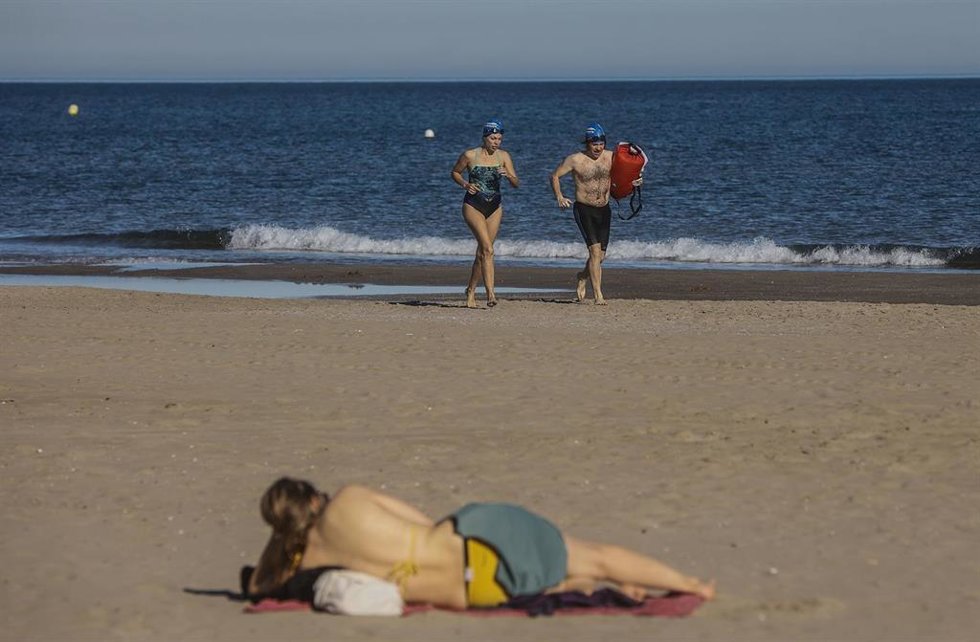 Archivo - Dos personas en bañador caminan por la orilla de la playa, en Valencia, Comunidad de Valencia, (España). 
