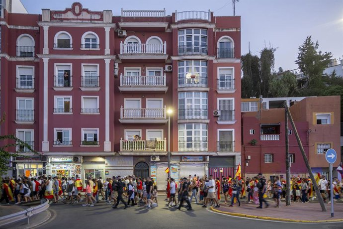 Várias pessoas exibem cravos e bandeiras da Espanha durante uma manifestação em frente à Delegação do Governo, em 28 de agosto de 2026, em Ceuta (Espanha). Cerca de cem ceutianos se reuniram esta tarde em frente à Delegação do Governo exibindo cravos