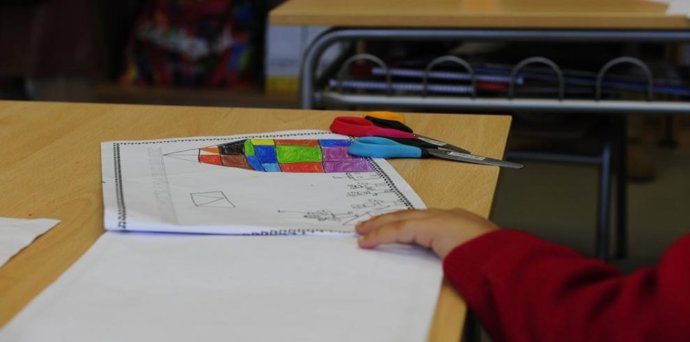 Un menor en un aula de infantil con material escolar.