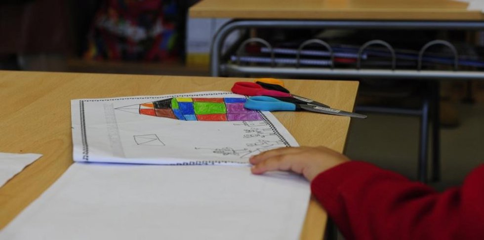 Un menor en un aula de infantil con material escolar.