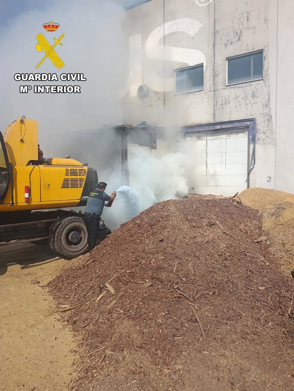 Agentes de la Guardia Civil sofocan el incendio en la nave.