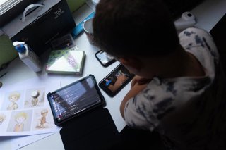 Archivo - Un niño usa el teléfono móvil y una tablet, a 18 de octubre de 2023, en Madrid (España). Según la Vanguardia, en España se estima que el 21% de los adolescentes es adicto a la red y casi la mitad reconoce que tiene "un contacto activo" cada 15 m