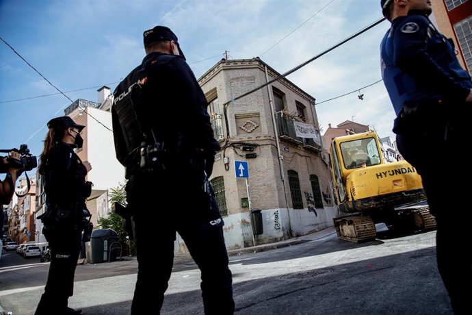 Archivo - Varios agentes de Policía Nacional frente a una máquina retroexcavadora durante la demolición de un edificio okupado