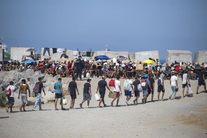 Decenas de migrantes caminan por la playa del Trampolín, a 31 de agosto de 2026, en Ceuta (España).