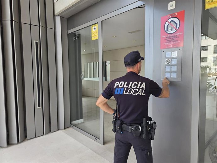 Agente de la Policia Local d'Eivissa frente a un bloque de viviendas.
