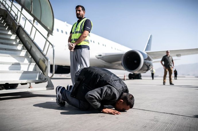 Archivo - En 2019, un solicitante de asilo afgano besa el suelo del aeropuerto tras bajar de un avión chárter.