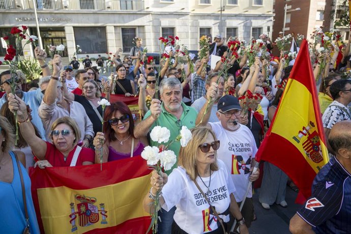 Numerosas personas portan claveles y banderas de España durante una manifestación ante la Delegación del Gobierno, a 28 de agosto de 2026, en Ceuta (España). 