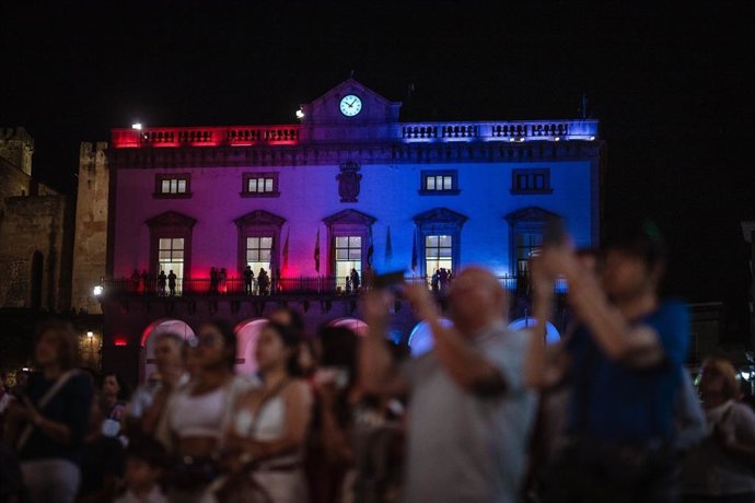 Fachada del Ayuntamiento de Cáceres iluminado con los colores rosa y azul de la Capitalidad Cultural