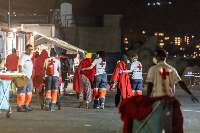Archivo - Trabajadores de la Cruz Roja reciben a personas rescatadas de un cayuco
