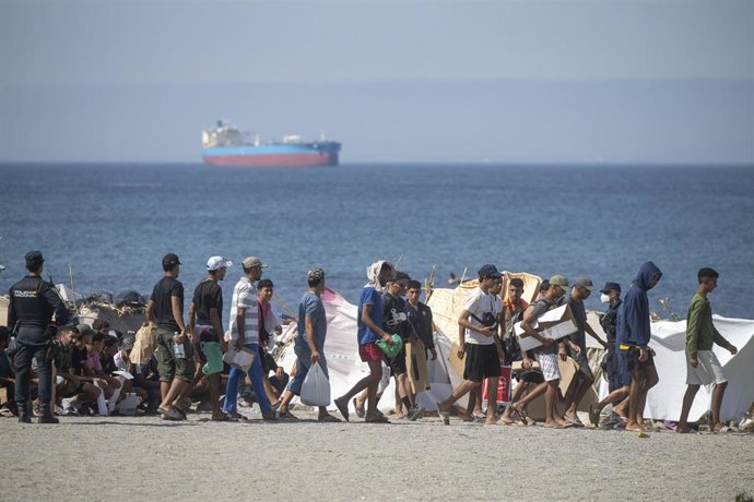 Decenas de migrantes caminan por la playa del Trampolín, en Ceuta