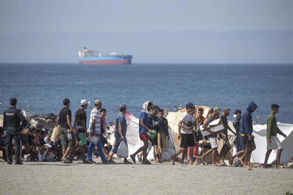 Decenas de migrantes caminan por la playa del Trampolín, en Ceuta