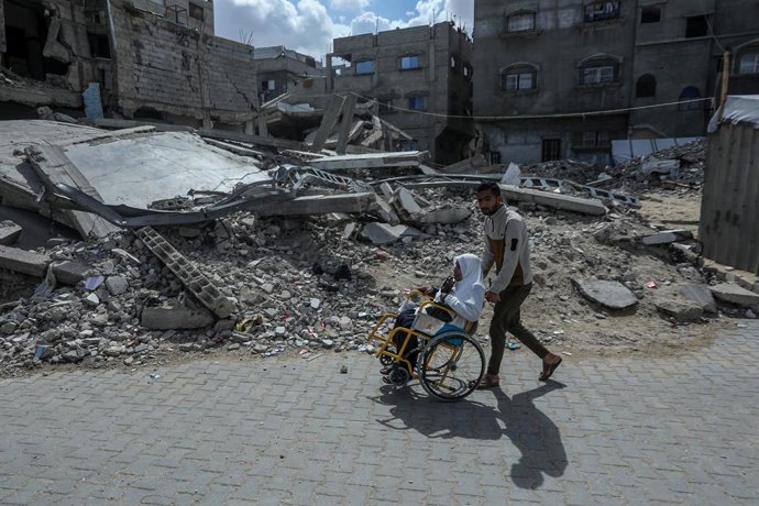 Archivo - Un joven empuja una la silla de una mujer tras un ataque israelí en Gaza.