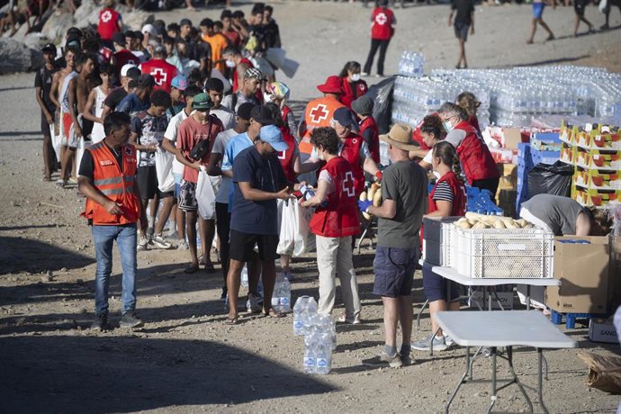 Miembros de la Cruz Roja reparten comida a los inmigrantes en una playa, a 21 de agosto de 2026, en Ceuta (España). Ceuta sigue afrontando una grave crisis humanitaria después de la histórica entrada masiva de más de 70.000 migrantes a nado por el Tarajal