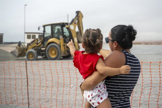 Dos personas observan la instalación de carpas de un nuevo espacio de acogida a migrantes 