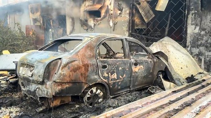 RÚSSIA, LUGANSK – 19 DE AGOSTO DE 2026: Os destroços carbonizados de um carro permanecem do lado de fora de um galpão de armazenamento danificado por um ataque militar ucraniano, que abrigava uma oficina mecânica e uma fábrica de doces. Captura de tela do