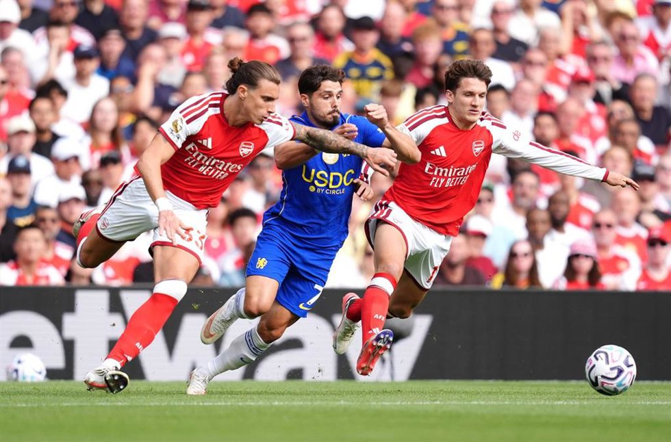 El extremo portugués del Chelsea Pedro Neto (centro) batalla por el balón ante el central del Arsenal Riccardo Calafiori (izquierda) y Christos Tzolis. 