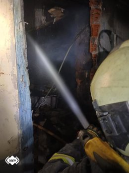 Un efectivo de Bomberos de Asturias trabaja en la extinción del fuego en una casa abandonada en La Trancada, en Grado.