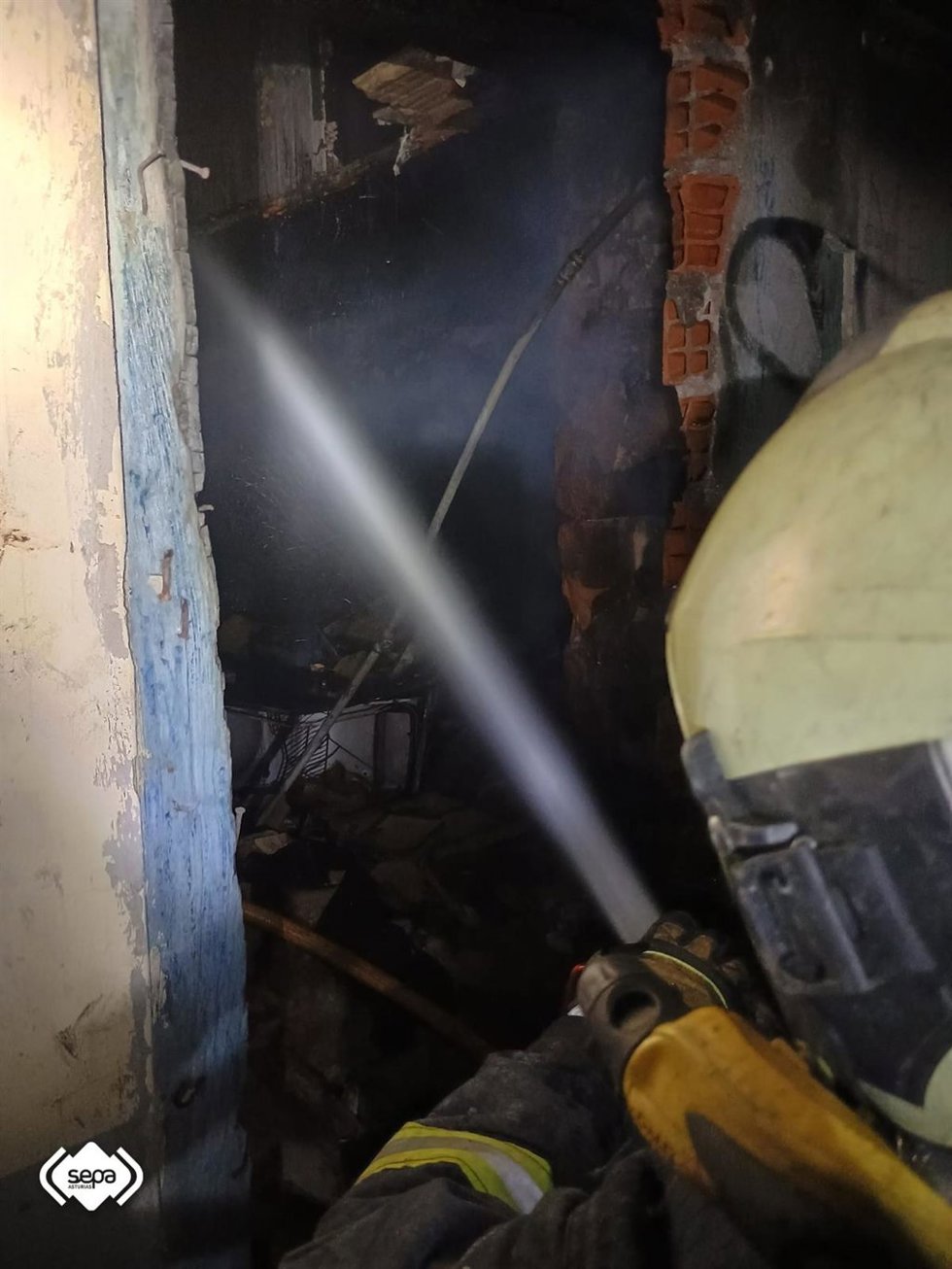Un efectivo de Bomberos de Asturias trabaja en la extinción del fuego en una casa abandonada en La Trancada, en Grado.
