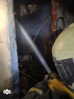 Un efectivo de Bomberos de Asturias trabaja en la extinción del fuego en una casa abandonada en La Trancada, en Grado.