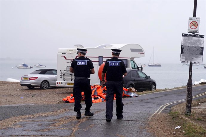 Agentes de policía pasan junto a un montón de chalecos salvavidas abandonados en Eastney Point, cerca de la playa de Eastney, en Portsmouth, tras una protesta celebrada anoche después de que se llevara al puerto a personas solicitantes de asilo.