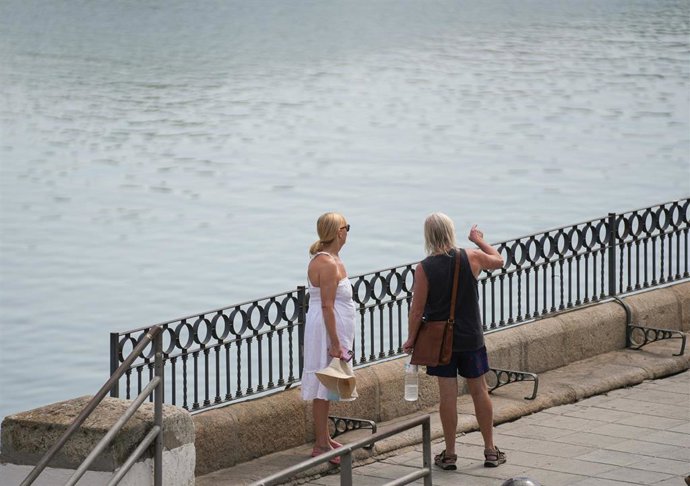 Archivo - Dos personas con ropa veraniega durante una jornada de intenso calor en Sevilla.