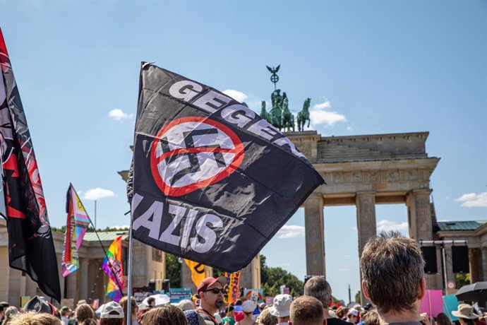 8 de agosto de 2026, Berlim, Berlim, Alemanha: Manifestantes seguram cartazes e bandeiras antinazistas criticando o partido de extrema direita Alternativa para a Alemanha (AfD) durante uma manifestação do PRUEF no Portão de Brandemburgo, em Berlim, Aleman