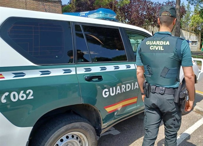 Archivo - Un agente y un coche de la Guardia Civil.