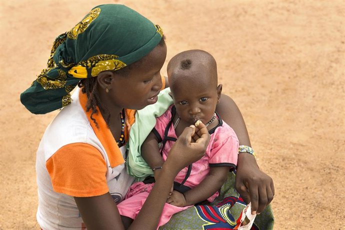 Archivo - Una madre da de comer a su hijo en Burkina Faso
