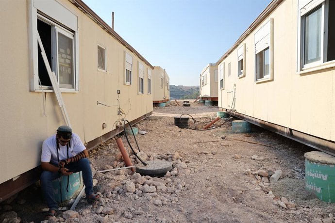 JERUSALÉM, 14 de agosto de 2026  -- Um colono judeu está sentado perto de casas pré-fabricadas no assentamento de Ganim, na Cisjordânia, em 13 de agosto de 2026.   Quatro assentamentos na Cisjordânia, incluindo Ganim, foram evacuados em 2005 como parte do