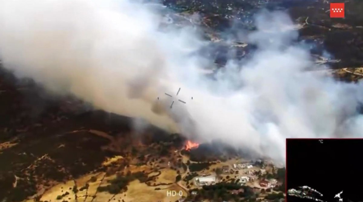 Bomberos de la Comunidad trabajan para extinguir un incendio en la M-505 a su paso por el río Cofio
