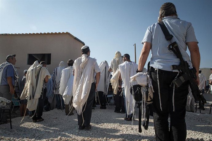 Archivo - Colonos israelíes armados con rifles asisten a una ceremonia para el restablecimiento del asentamiento de Ganim, en Cisjordania