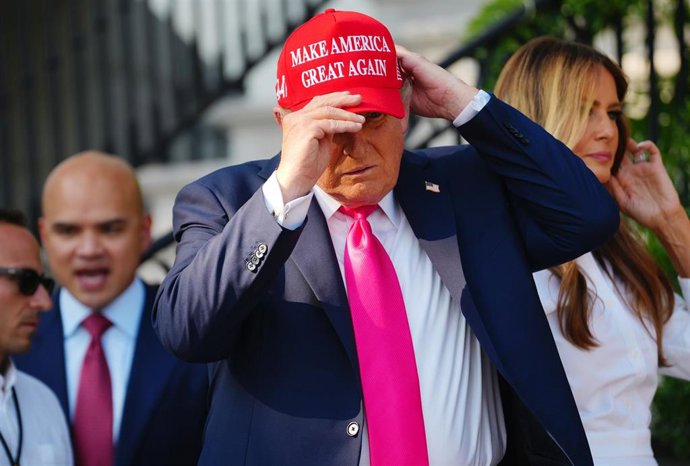 Archivo - El presidente de Estados Unidos, Donald Trump, se coloca una gorra con el lema 'Make America Great Again' (MAGA)