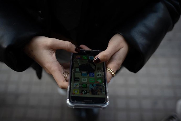 Archivo - Una joven usa el teléfono móvil.