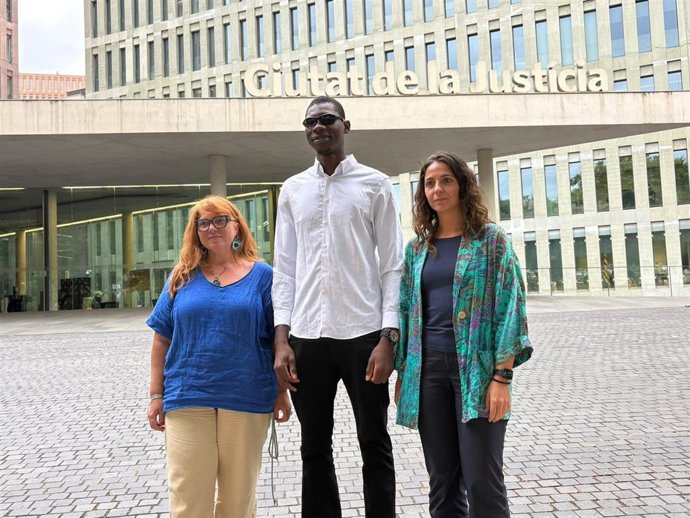 La psicóloga de Irídia, Paula Rossi; Zakaria, agredido en Melilla en 2022, y la coordinadora de litigios de Irídia, Sònia Olivella, frente a la Ciutat de la Justícia de L'Hospitalet de Llobregat (Barcelona), a 9 de septiembre de 2026