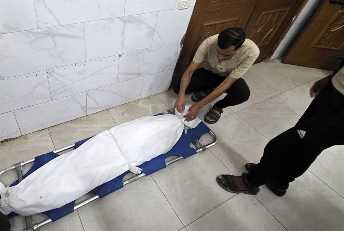 Palestins junt amb el cadàver d'una persona morta per un bombardeig d'Israel contra Jan Junis, en el sud de la Franja de Gaza, malgrat l'alto el foc en vigor des d'octubre del 2025