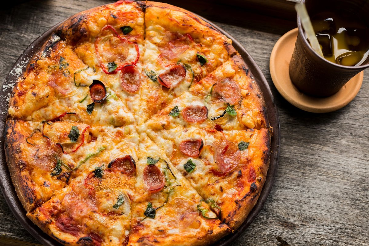 Pizza recién horneada sobre una mesa de madera.