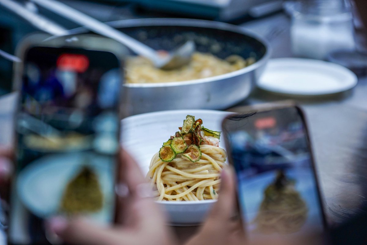 Dos móviles fotografían un plato de pasta.
