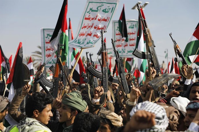 Arquivo - 5 de janeiro de 2024, SANAA, Sanaa, Iêmen: 5 de janeiro de 2024, Sanaa, Iêmen: Um grupo de pessoas empunha armas, agita uma bandeira palestina e entoa slogans durante uma manifestação em memória dos dez combatentes houthis mortos pela Marinha do